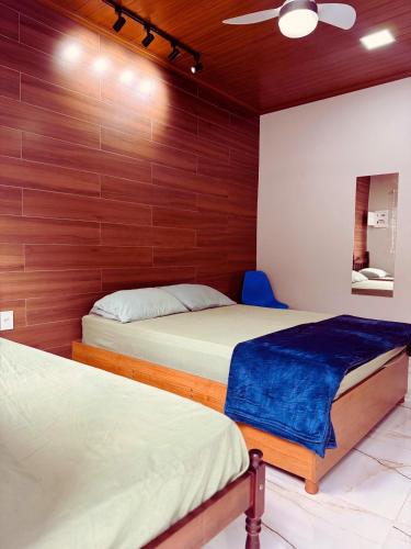 two beds in a room with wood paneled walls at Ares da Bocaina Suítes in Bananal