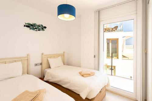two beds in a room with a window at Breathtaking Bay views Nerja in Torrox