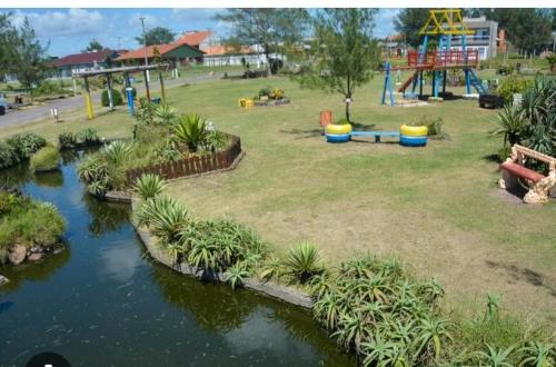 a park with a river and a playground at Casa Térrea de praia confortável para famílias in Tramandaí