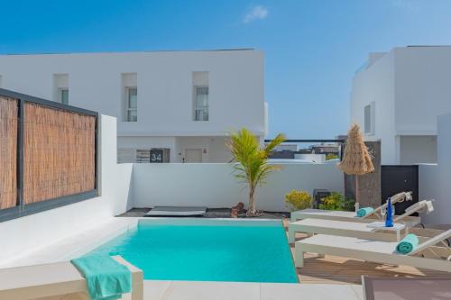 a swimming pool in a room with tables and chairs at Villa Serena Blanca by Villalia Luxury Oasis & Private Pool in Playa Blanca