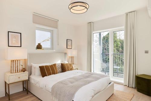 a white bedroom with a bed and a window at 2-Bed Apartments a Short Walk to Wembley Stadium in London