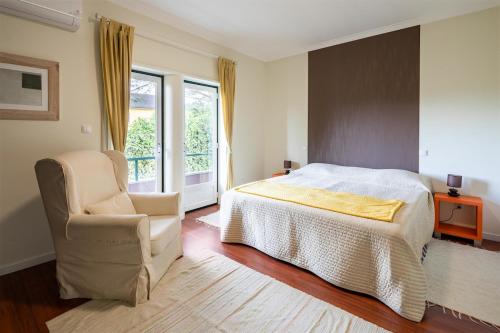 ein Schlafzimmer mit einem Bett, einem Stuhl und einem Fenster in der Unterkunft Casa Carvalho de Bouça, Moreira Monção 