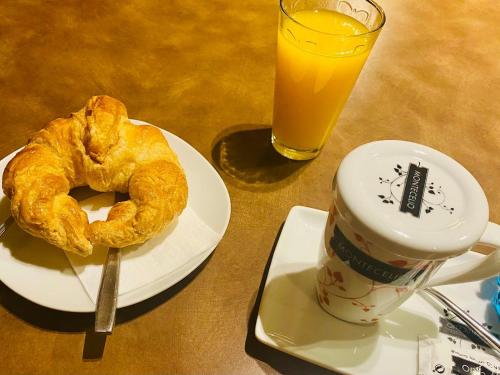 Un plato con un pastel y una taza de jugo de naranja en Hotel Spa Galatea, en Burela de Cabo