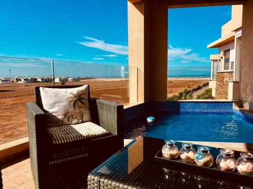 a patio with a table and chairs and a swimming pool at Ocean Gem - Exclusive 2BR, Balcony Pool, Beach, Surf & Views in Bouznika