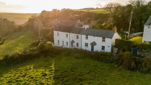 ein weißes Haus auf einem grünen Hügel in der Unterkunft 1 Rock Cottages in Treknow