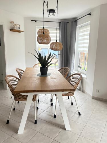 einem Esstisch mit Stühlen und einer Topfpflanze in der Unterkunft Neu Ferienhaus Sielbude Neßmersiel mit Garten und Wallbox allergikerfreundlich in Neßmersiel