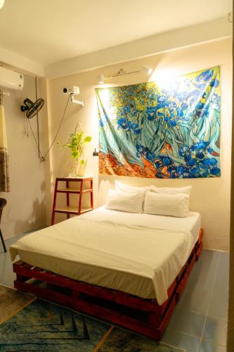 a bed in a room with a painting on the wall at Bụi Homestay - Ferry to Rạch Giá in Rạch Giá