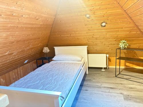 ein Schlafzimmer mit einem Bett in einem Holzzimmer in der Unterkunft Neu Ferienhaus Sielbude Neßmersiel mit Garten und Wallbox allergikerfreundlich in Neßmersiel