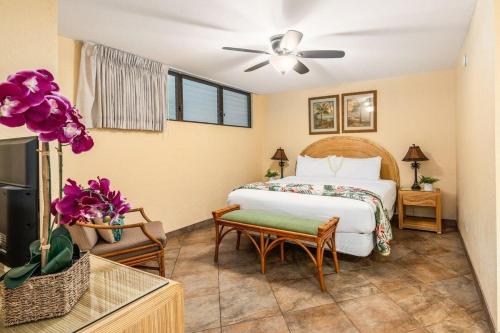 a bedroom with a bed and a table and flowers at Papakea K103 · PK K103 Ocean views Condo | Lanai + AC + Pool in Kaanapali