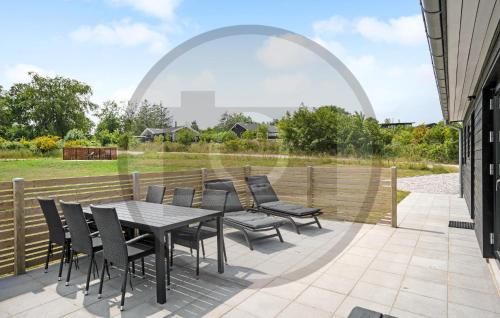 Un patio con mesa y sillas y una valla. en 6 Bedroom Awesome Home In Glesborg, en Fjellerup Strand