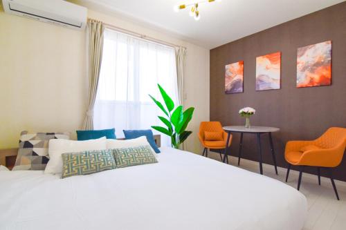 a bedroom with a white bed and orange chairs at KAWAII House -Free Parking- in Osaka