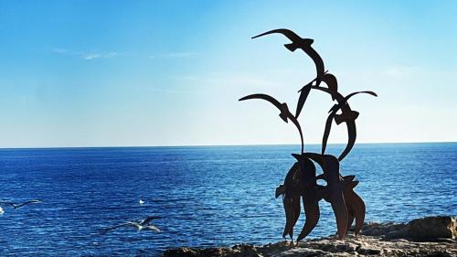 a statue of a plant on a rock near the ocean at Calamora-Moraira in Moraira