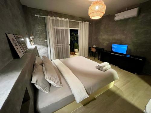 a bedroom with a large bed and a television at The Summer Cottage Koh Chang in Khlaung Phai Bae