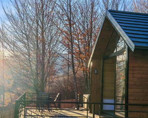 a cabin with a deck with a table and chairs at Boga Chalet in Bogë