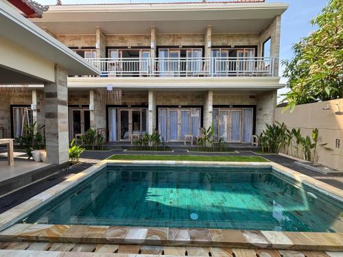 a villa with a swimming pool in front of a house at Casa Benoa Homestay in Nusa Dua