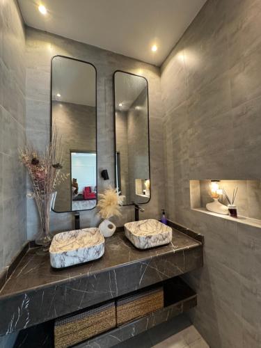 two sinks in a bathroom with two mirrors at Lamour Villa in Şallān