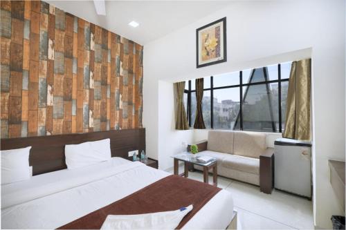 Un dormitorio con una cama y un sofá y una ventana. en Hotel PALMVIEW RESIDENCY, en Vadodara
