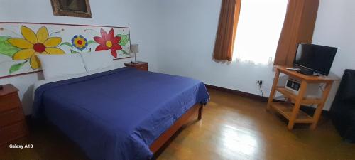 a bedroom with a blue bed and a television at Kurumi Hostel in Cusco
