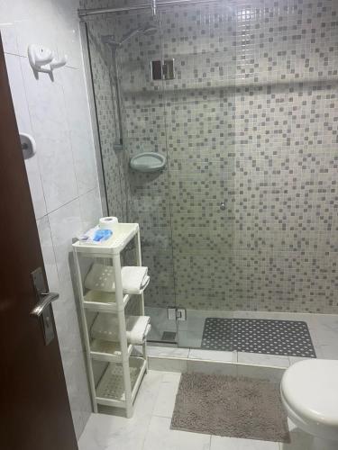 a bathroom with a shower with a toilet and a shelf at comfort private master room in Sharjah