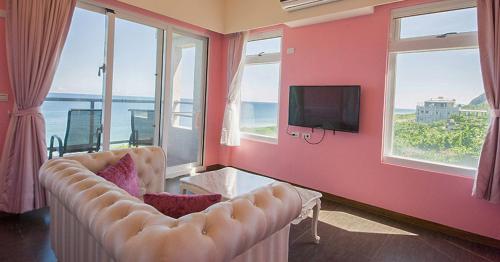 a living room with a couch and a tv and windows at Whitecaps B&B in Yanliau