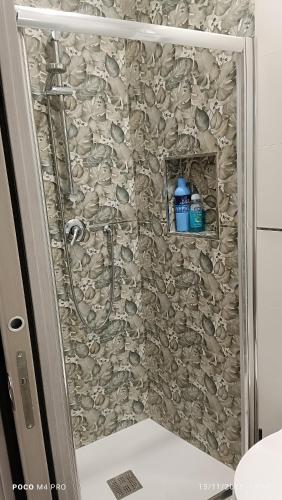 a shower in a bathroom with a stone wall at Grotthouse in Andria