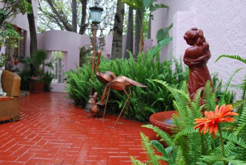 a garden with a red brick walkway with a statue at Ronique's Guest House in Rustenburg