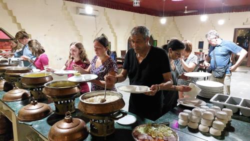 eine Gruppe von Menschen, die in einer Küche stehen und Essen zubereiten in der Unterkunft Dune safari camp & resort in Sām