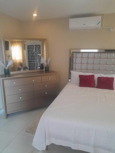 a bedroom with a large white bed with red pillows at Bobby Vacational Home in Portmore