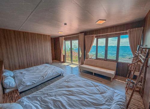 1 Schlafzimmer mit 2 Betten, einer Bank und Fenstern in der Unterkunft Rio Skyhouse in Ấp Trạm Hành