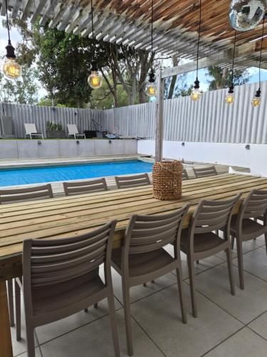 einen Holztisch und Stühle neben einem Pool in der Unterkunft The Compass in Marina da Gama