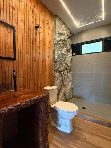 a bathroom with a toilet and a stone wall at Finca cerca a Cali El Paraíso de Salo in Papagalleros