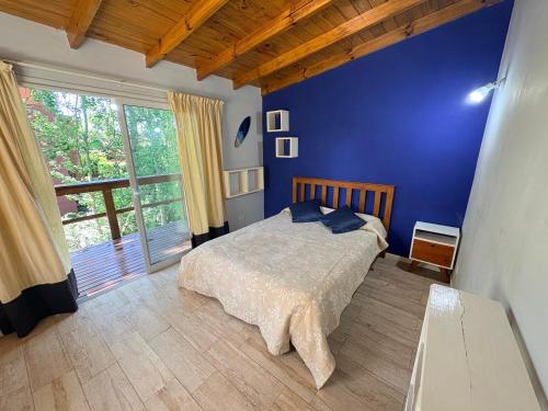 a blue bedroom with a bed and a large window at Dpto amplio en la naturaleza cerca del mar y del centro de Pinamar in Ostende