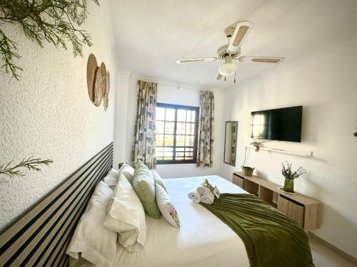 Schlafzimmer mit einem Bett mit Kissen und einem TV in der Unterkunft Verano Eterno Balcon del Mar by Deihu Experiences in Arona