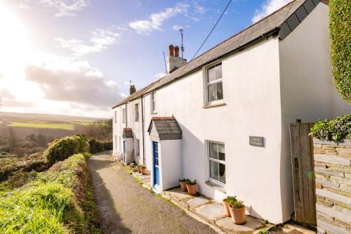a white house with a blue door on a street at 1 Rock Cottages in Treknow