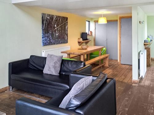 a living room with a black couch and a table at Bothy 2 - Uk50472 in Greenhaugh