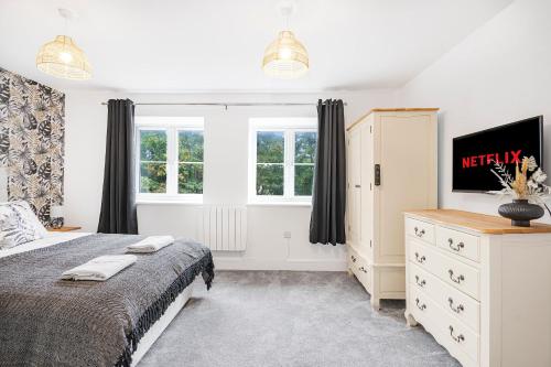 a bedroom with a bed and a dresser and windows at The Roost Group - 5 Bed House Hot Tub Near Beach in St. Leonards