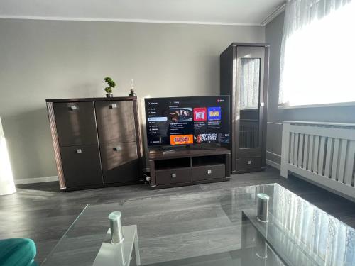 ein Wohnzimmer mit einem TV und einem Entertainment-Center in der Unterkunft Trzy pokojowe mieszkanie przy UMK ,kilka przystanków od starego Miasta in Toruń