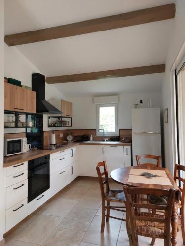 Una cocina con gabinetes blancos y una mesa con sillas. en La Clemensane, en Lacoste