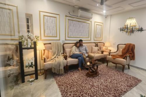 twee mensen zitten op een bank in een woonkamer bij Hotel Broholi Height Inn Near Hafeezpet Railway Station in Hyderabad