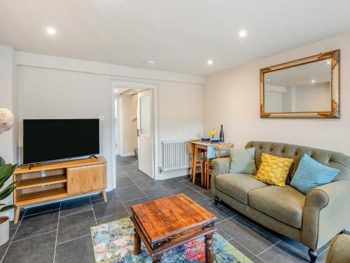 a living room with a couch and a flat screen tv at The Cottage At Number One in Caerwys