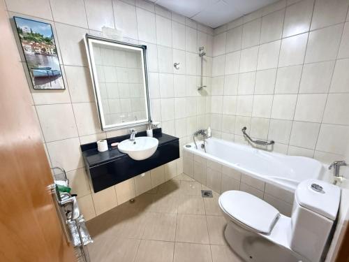 a bathroom with a sink and a tub and a toilet at Lavender Oasis - Entire Spacious 1 flat in Jumeirah Village Circle in Dubai