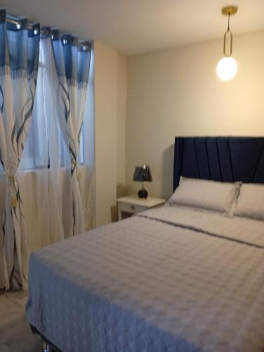 a bedroom with a bed and a window with curtains at Adel 2 Ovalo Larco Departamento in Trujillo
