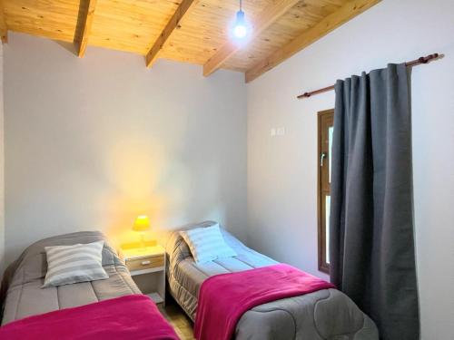 a bedroom with two beds and a desk with a window at Village De Las Sierras in Sierra de la Ventana