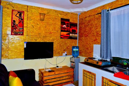 Hakuna Matata Gardens في Migori: غرفة معيشة فيها تلفزيون على جدار