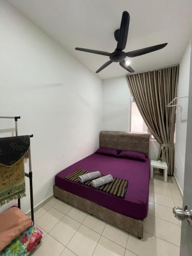 a bedroom with a purple bed with a ceiling fan at d'Ruma Homestay Alor Gajah in Kampong Jelatang