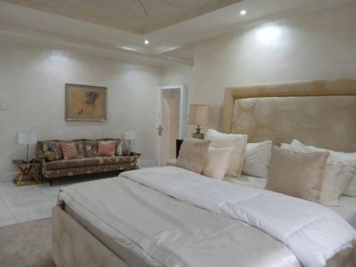 a white bedroom with a large bed and a couch at Vaj in Lagos