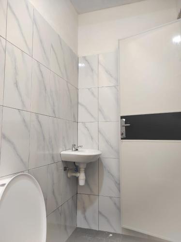 a white bathroom with a sink and a toilet at Embun Pagi Alami in Telukladang