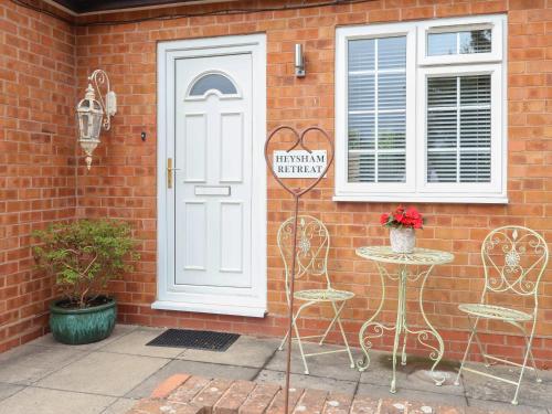 a brick house with a white door and a table and chairs at Heysham Retreat in Evesham