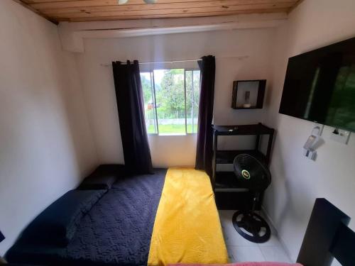 a bedroom with a window and a bed with a yellow blanket at Kitnet dos netos in Ubatuba