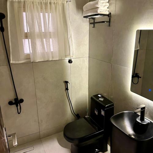 a bathroom with a black toilet and a sink at نسيم الحرم 2 in Ash Shishah